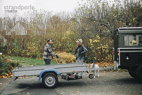 Weibliche und männliche Freunde unterhalten sich  während sie neben einem Geländewagen stehen