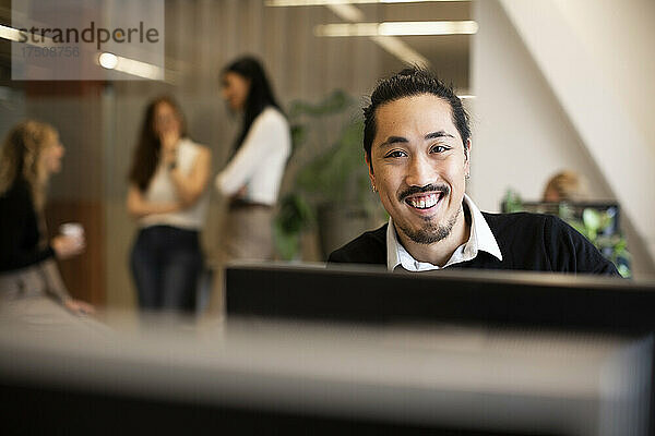 Porträt eines lächelnden Geschäftsmannes bei der Arbeit im Büro