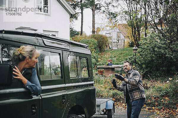 Mann  der seine Freundin anleitet  den Geländewagen in der Einfahrt rückwärts zu fahren