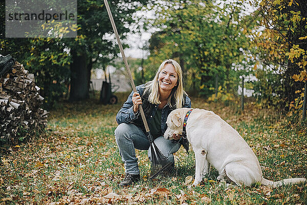 Lächelnde reife Frau mit Hund  die im Hinterhof wegschaut