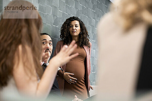 Schwangere Managerin diskutiert mit Kollegen bei der Planung der Strategie in einer Sitzung im Büro