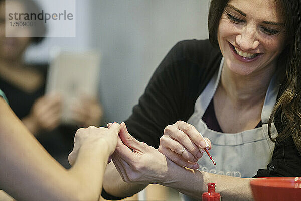 Frau lässt sich in einem Nagelstudio die Nägel lackieren.