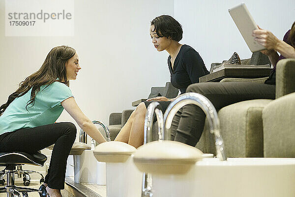 Frau bei der Pediküre mit einer Nageltechnikerin in einem Nagelstudio.