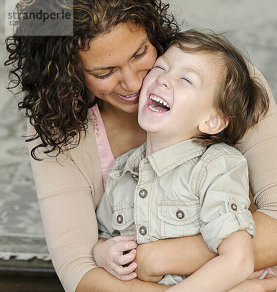 Frau  die einen Jungen umarmt  Mutter und Sonne lachen.