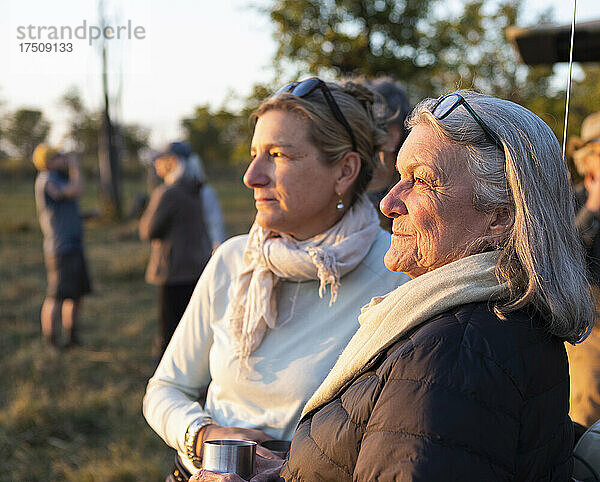 Zwei Menschen  eine reife Frau und ihre Mutter  stehen bei Sonnenuntergang nebeneinander