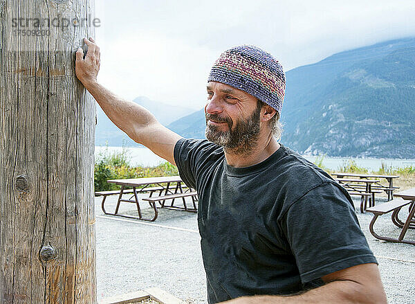 Mann auf einem Picknickplatz in den Bergen mit gestrickter Mütze.