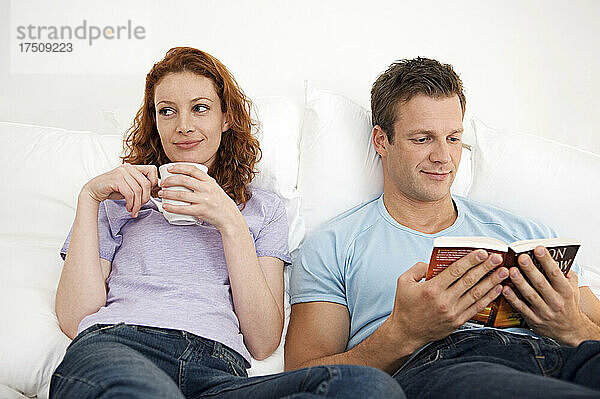 Mann und Frau entspannen zusammen  Frau mit einer Tasse  Mann liest ein Buch.