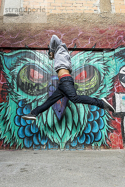 Junger Mann springt vor Graffiti in die Luft