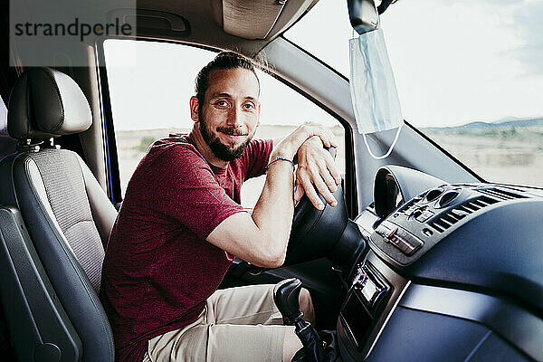 Lächelnder Mann  der während COVID-19 im Auto sitzt