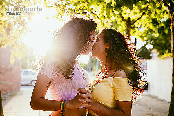 Romantische Lesben küssen sich  während sie an einem sonnigen Tag in der Stadt stehen