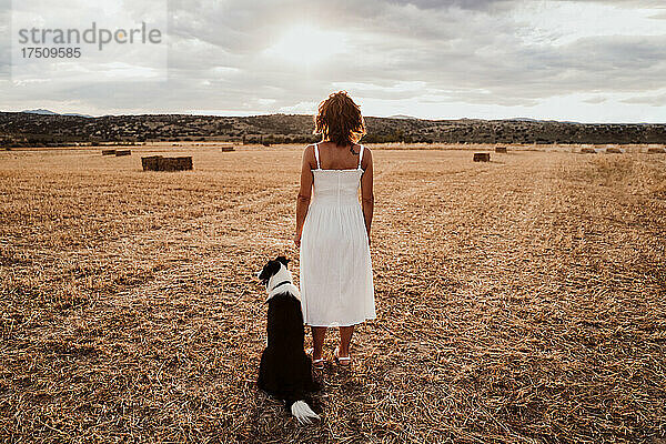 Frau steht neben Hund im Feld