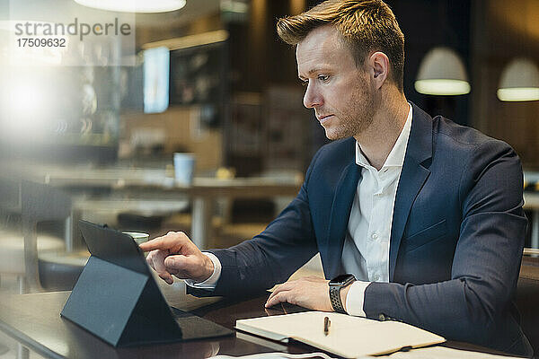 Geschäftsmann nutzt digitales Tablet am Tisch im Café