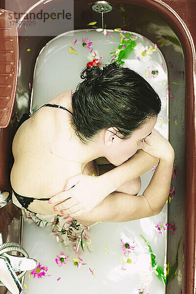 Woman taking a milk bath with blossoms