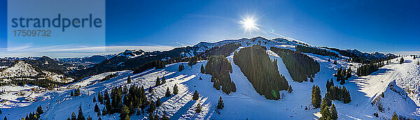 Helikopter-Panorama der Sonne  die über schneebedeckten Gipfeln im Mangfall-Gebirge scheint