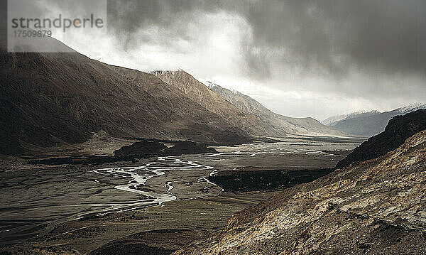 Indien  Ladakh  Wolken über einem schmalen Bach  der durch das Tal im Himalaya fließt