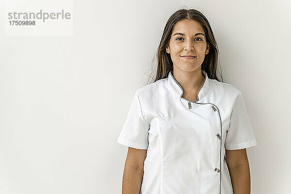 Lächelnde Krankenschwester gegen die Wand in der Zahnarztpraxis