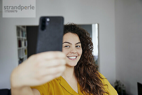 Glückliche junge schöne Frau  die zu Hause ein Selfie macht