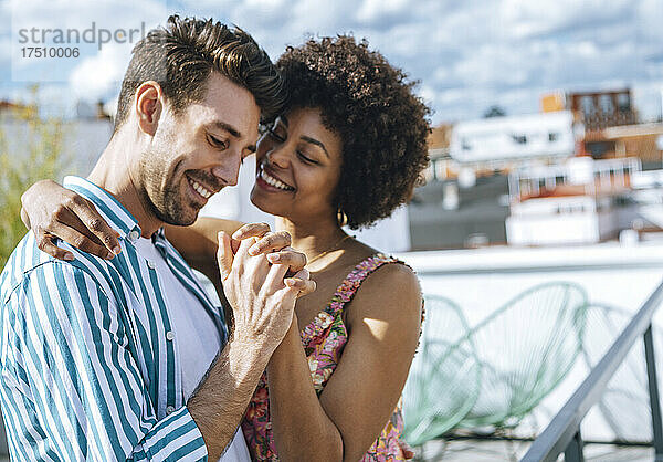 Romantisches multiethnisches Paar tanzt auf der Penthouse-Terrasse