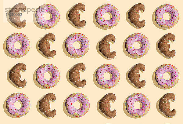 3D-Illustration  gefälschte Croissants und Donuts aus Plüsch auf cremefarbenem Hintergrund