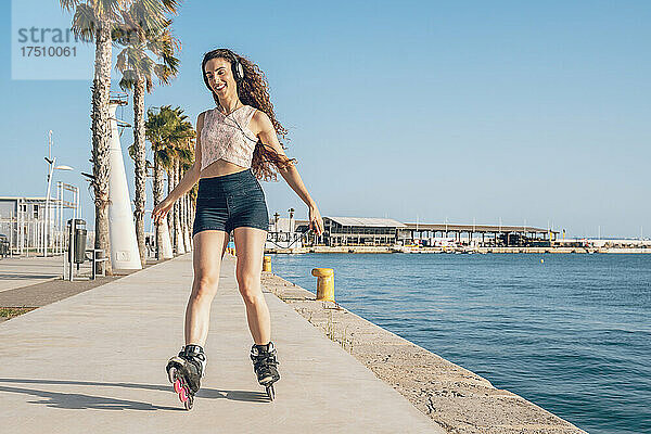 Junge Frau beim Inline-Skaten auf der Küstenpromenade