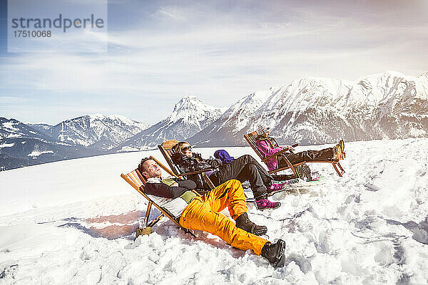 Freunde sonnen sich im Liegestuhl in der Berglandschaft im Winter  Achenkirch  Österreich