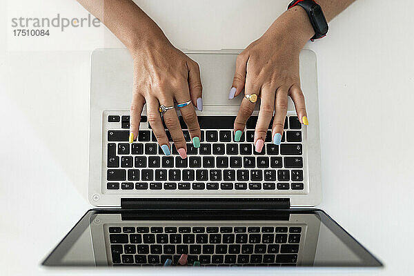 Nahaufnahme von Frauenhänden  die zu Hause einen Laptop auf dem Tisch benutzen
