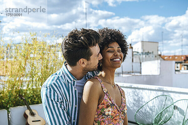 Glückliches multiethnisches Paar verbringt schöne Zeit auf der Penthouse-Terrasse