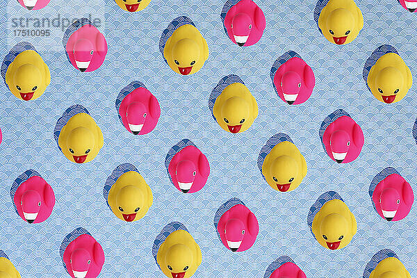 Gelbe Enten und rosa Flamingos als Badespielzeug auf blauem Hintergrund.