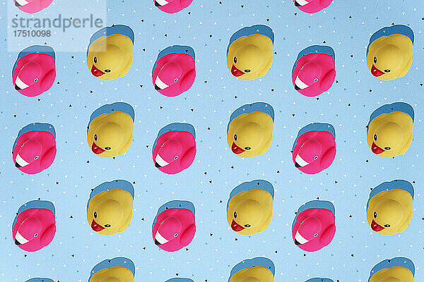 Gelbe Enten und rosa Flamingos als Badespielzeug auf blauem Hintergrund.