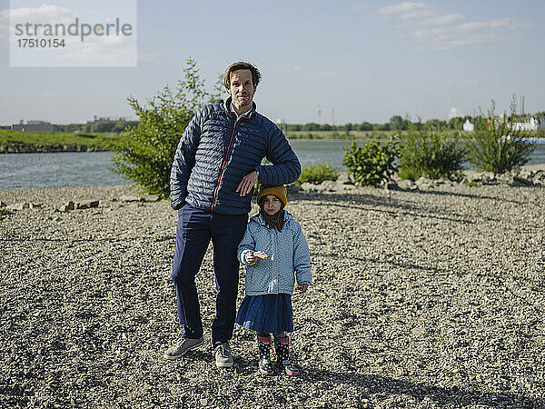 Vater und Tochter stehen an einem sonnigen Tag an Land am Rhein