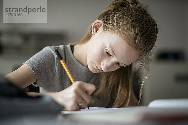 Mädchen lernt zu Hause und schreibt in ein Übungsheft
