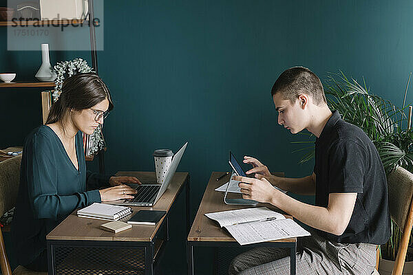 Junge Männer und Frauen arbeiten zu Hause an Schreibtischen