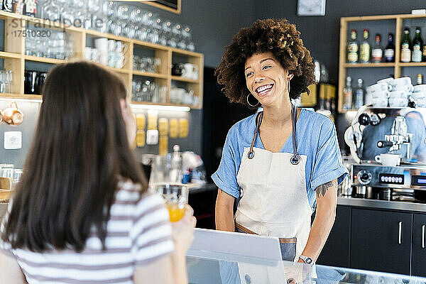 Glückliche Besitzerin spricht mit einer jungen Frau an der Theke im Café