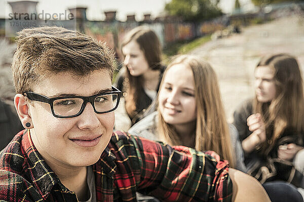 Porträt eines lächelnden Teenagers  der mit Freunden in einem alten  heruntergekommenen Industriegebiet herumhängt