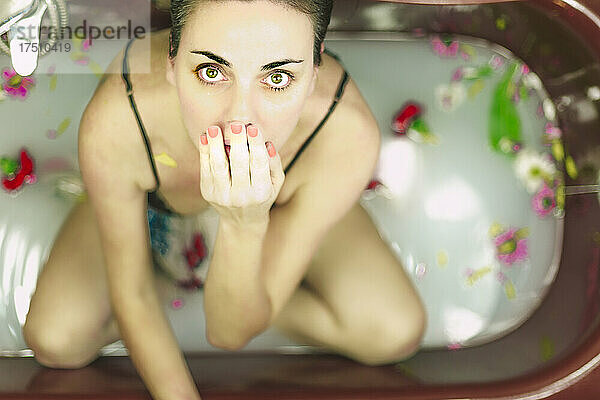 Porträt einer Frau  die ein Milchbad mit Blüten nimmt