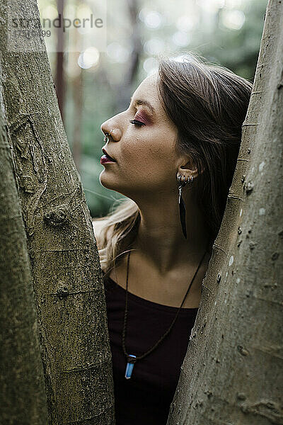 Porträt einer jungen Frau mit geschlossenen Augen am Baum