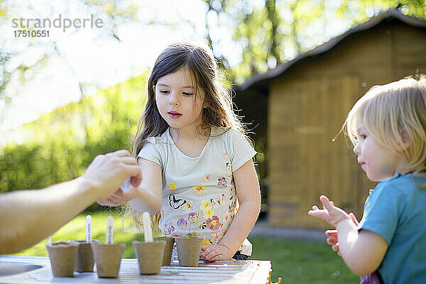 Vater schenkt Mädchen Samen  während er auf dem Tisch im Garten arbeitet