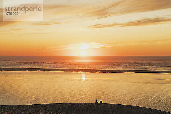 Silhouette eines Paares  das den Sonnenuntergang am Atlantik  der Düne von Pilat  Nouvelle-Aquitaine  Frankreich beobachtet