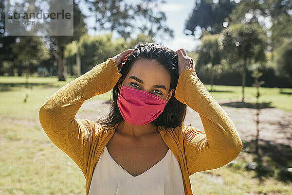 Nahaufnahme einer jungen Frau mit Maske  die an einem sonnigen Tag im Park steht