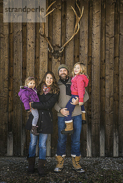 Porträt einer lächelnden Familie vor einer Hütte mit Hirschgeweihen