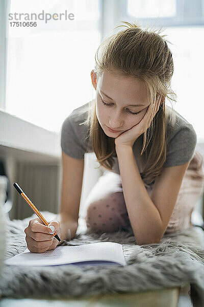 Mädchen lernt zu Hause und schreibt in ein Übungsheft