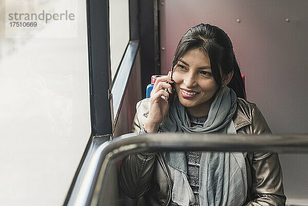 Lächelnde Frau telefoniert während der Busfahrt
