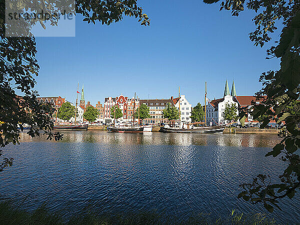 Deutschland  Schleswig-Holstein  Lübeck  Boote vertäut am Traveufer mit Gebäuden von Travemünde im Hintergrund