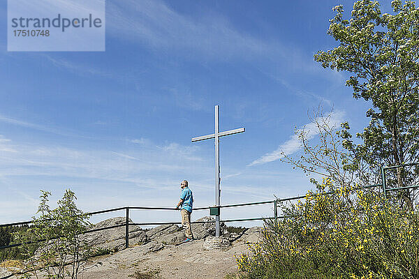 Deutschland  Nordrhein-Westfalen  Monschau  Mann bewundert die Aussicht an einem Kreuz  das auf dem Gipfel des Ehrensteinley steht