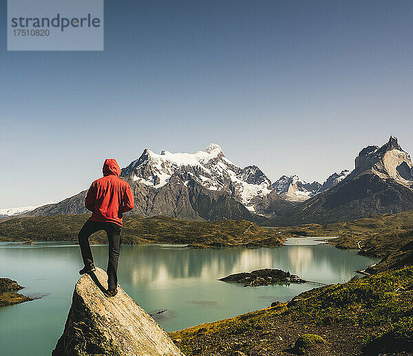 Mann in Kapuzenjacke steht auf einem Felsen am Pehoe-See im Nationalpark Torres Del Paine  Chile  Patagonien  Südamerika
