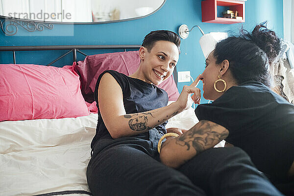 Lächelnde Frau spricht im Schlafzimmer mit ihrem Partner