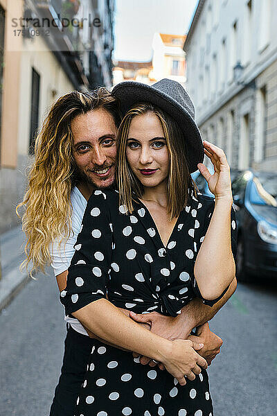 Stilvolles romantisches Paar umarmt sich  während es auf der Straße in der Stadt steht