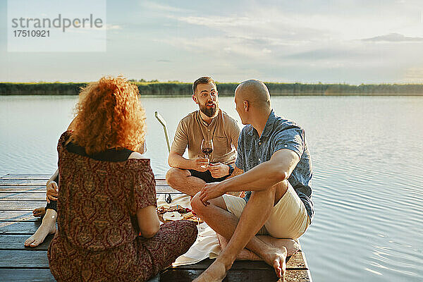 Freunde beim Picknick am Steg an einem See