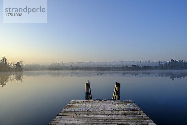 Steg am Ufer des Kirchsees im nebligen Morgengrauen