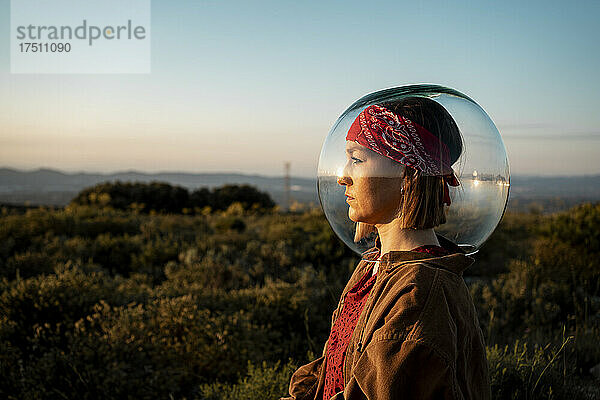 Woman with a fish bowl on her head in the countryside